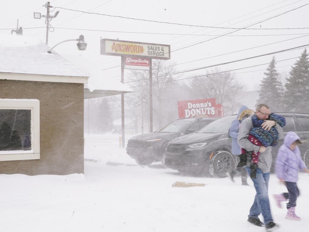 A family huddled together, moves quickly to their car, to get out of the frigid cold from a massive winter storm affecting most of the USA., in Flint, Michigan. Picture: Getty Images