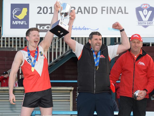 Red Hill captain Marcus Dal Lago and coach Jamie Mollo lift the 2019 MPNFL Division 2 premiership cup as club stalwart Owen Shaw looks on. Picture: Chris Eastman