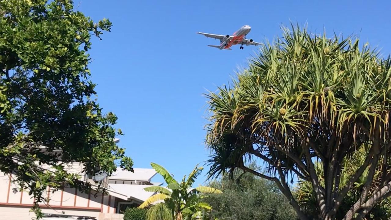An aircraft flies over houses at Mudjimba on approach to Sunshine Coast Airport.