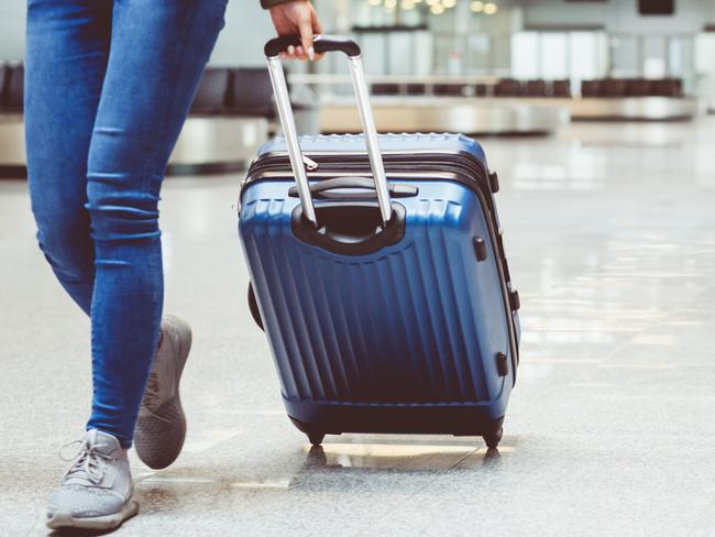 Woman in international airport walking with luggage. Close up of legs, unrecognizable person.Photo - istockESCAPE6 MARCH 2022 COVER FEATURE DOC HOLIDAY FLYING TRAVEL