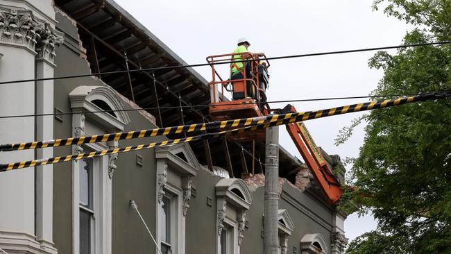 Workers inspect the damaged facade of Betty Burgers' building.