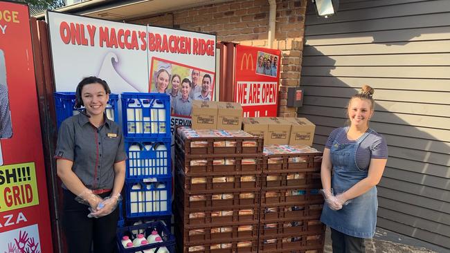 McDonald's Bracken Ridge team members (from left) Talitha Dalton and Caitlyn Menesi with some of the bread and milk which they gave away on Saturday, April 11, 2020.