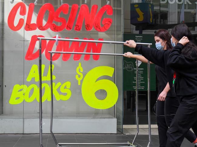 Workers push trolleys past an empty shop in Melbourneâs central business district on August 3, 2020 after the state announced new restrictions as the city battles fresh outbreaks of the COVID-19 coronavirus. - lia's Victoria state imposed fresh, sweeping restrictions on August 2, 2020, including a curfew in Melbourne for the next six weeks, a ban on weddings, and schools and universities going back online in the coming days. (Photo by William WEST / AFP)