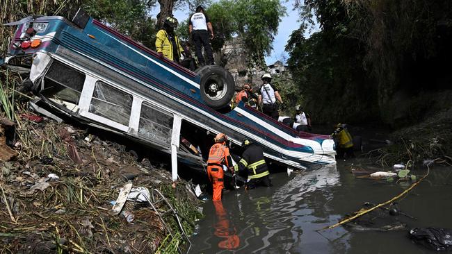 Firefighters work at the scene where a bus fell down a ravine in Guatemala City. Picture: AFP