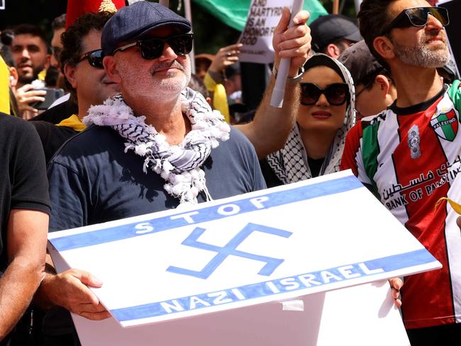 SYDNEY, AUSTRALIA - NewsWire Photos OCTOBER 6, 2024: A protester pictured holding  a flag that has a Nazi like symbol on it at the protest in Hyde Park. Protestors gather at Hyde Park in Sydney's CBD to demand an end to the ongoing war and Israel's current occupation of Gaza, and the escalating Israel-Lebanon conflict. PICTURE SHOWS Al Yazbek Picture: NewsWire / Damian Shaw