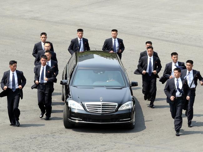 North Korean bodyguards jog next to a car carrying North Korea's leader Kim Jong Un returning to the North for a lunch break after a morning session of the inter-Korean summit at the truce village of Panmunjom. Picture: AFP