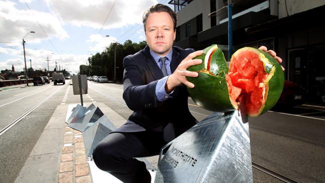 Westgarth Traders association president Peter Lynch breaks a watermelon on the controversial installation.