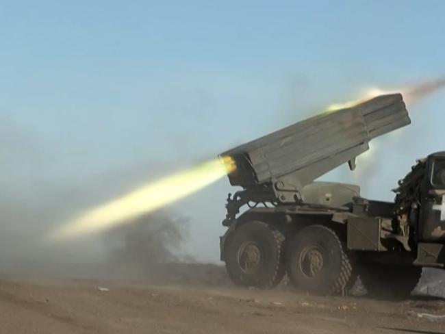 This grab taken from AFP video footage shows a member of Ukraine's military looking away as a BM-21'Grad' MLRS 122mm rocket launcher fires on the outskirts of Soledar on January 11, 2023. - Ukrainian President Volodymyr Zelensky has said fighting is still raging in a key eastern frontline city that a Russian mercenary group earlier said it controlled, as Moscow announced a new military commander in Ukraine. The fate of Soledar in eastern Ukraine was uncertain after Russian group Wagner claimed it controlled the gateway town -- but the Kremlin cautioned against declaring victory prematurely. (Photo by Arman SOLDIN / AFP)