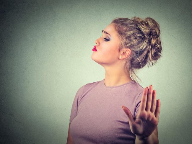 Snobby young annoyed angry woman with bad attitude giving talk to hand gesture with palm outward isolated grey wall background. Negative human emotion face expression feeling body language