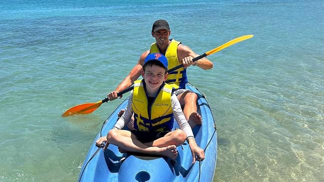 Premiership star Scott Pendlebury being put to work on a kayak in Fiji, pictured with son Jax.