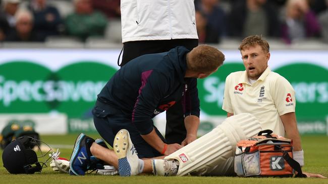 England captain Joe Root gets attention after being hit on the leg by Pat Cummins. Picture: AFP