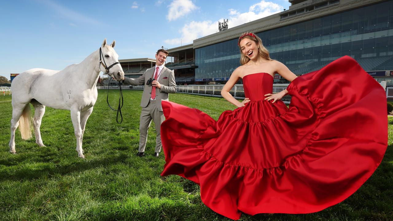 Anna Lynn, in a Jason Greco dress, and Tate Short, in an Arthur Galen suit, are excited about Caulfield’s cut-price tickets announcement. Pictured with former racehorse Bare at Caulfield Racecourse. Picture: David Caird