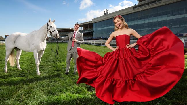 Anna Lynn, in a Jason Greco dress, and Tate Short, in an Arthur Galen suit, are excited about Caulfield’s cut-price tickets announcement. Pictured with former racehorse Bare at Caulfield Racecourse. Picture: David Caird