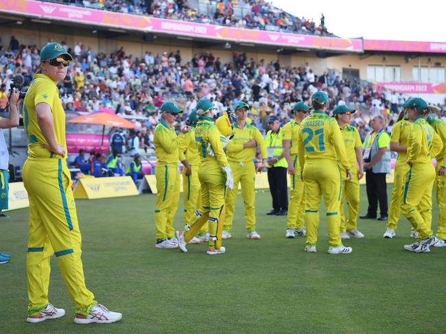 Players of Team Australia huddle as teammate Tahlia McGrath keeps her distance after testing positive for Covid. Picture: Alex Davidson / Getty Images