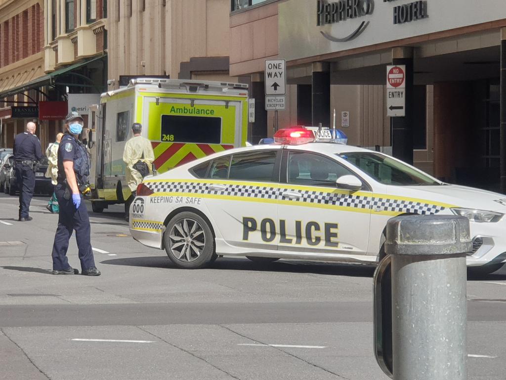 Police escort an individual from the Peppers Hotel in Waymouth St as part of the hotel quarantine program. Picture: Colin James