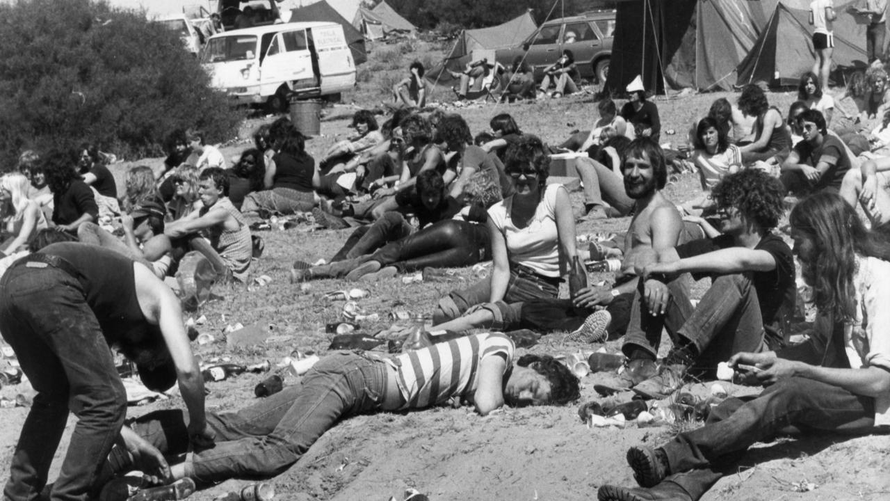 Music fans at Ponde rock music festival, held by the Hell's Angels Motorcycle Club in Ponde near Mannum, SA. The combination of sunshine and alcohol became too much for some members of the audience, such as this man who didn't flinch when an organiser cleaning away rubbish started putting cans and bottles on his legs, 11 Oct 1981.