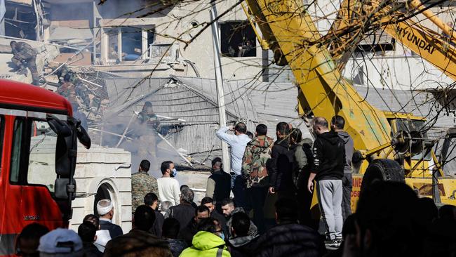 People and security forces gather in front of a building destroyed in a reported Israeli strike in Damascus on Saturday. Four Iranian military personnel are said to have died. Picture: Louai Beshara / AFP