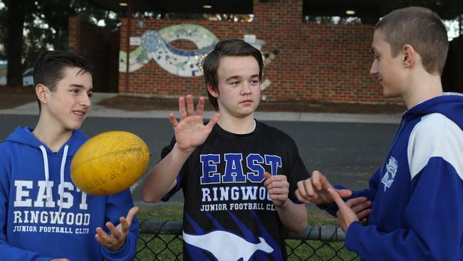 Deaf footballer Max Beasley, 14, centre, teaches a few signs to his East Ringwood Roos teammates Satchi Halit and Joel Tanzen. Picture: STUART MILLIGAN.