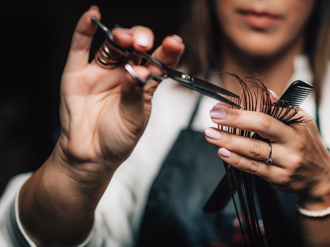 Close-up of a hairdresser cutting woman’s hair.