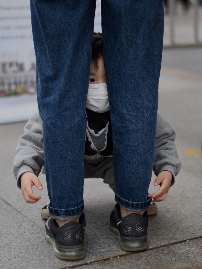 A child wearing a face mask peers past the legs of a guardian after arriving at the Hankou railway station in Wuhan. Picture: AFP