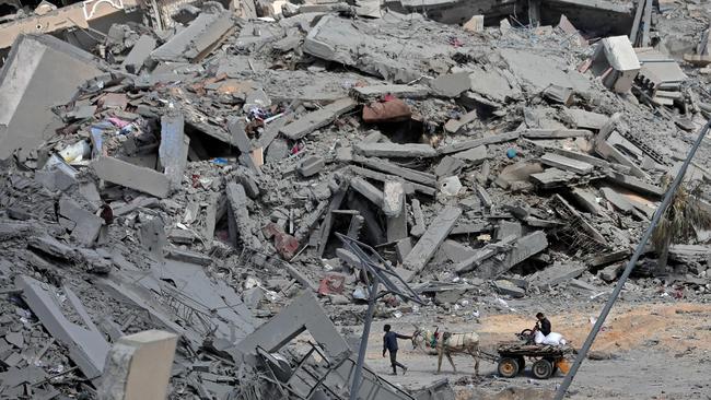 Displaced Palestinians move through a street amid the rubble of houses destroyed by Israeli bombardment in Hamad area, west of Khan Younis in the southern Gaza Strip on March 14. Picture: AFP