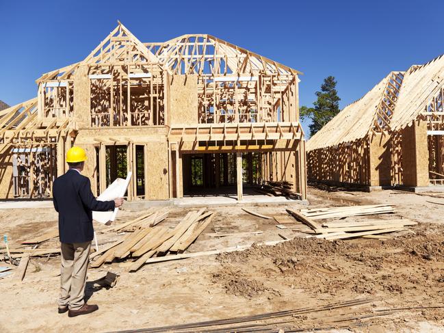 Developing Queensland - New home construction site with contractor in foreground.