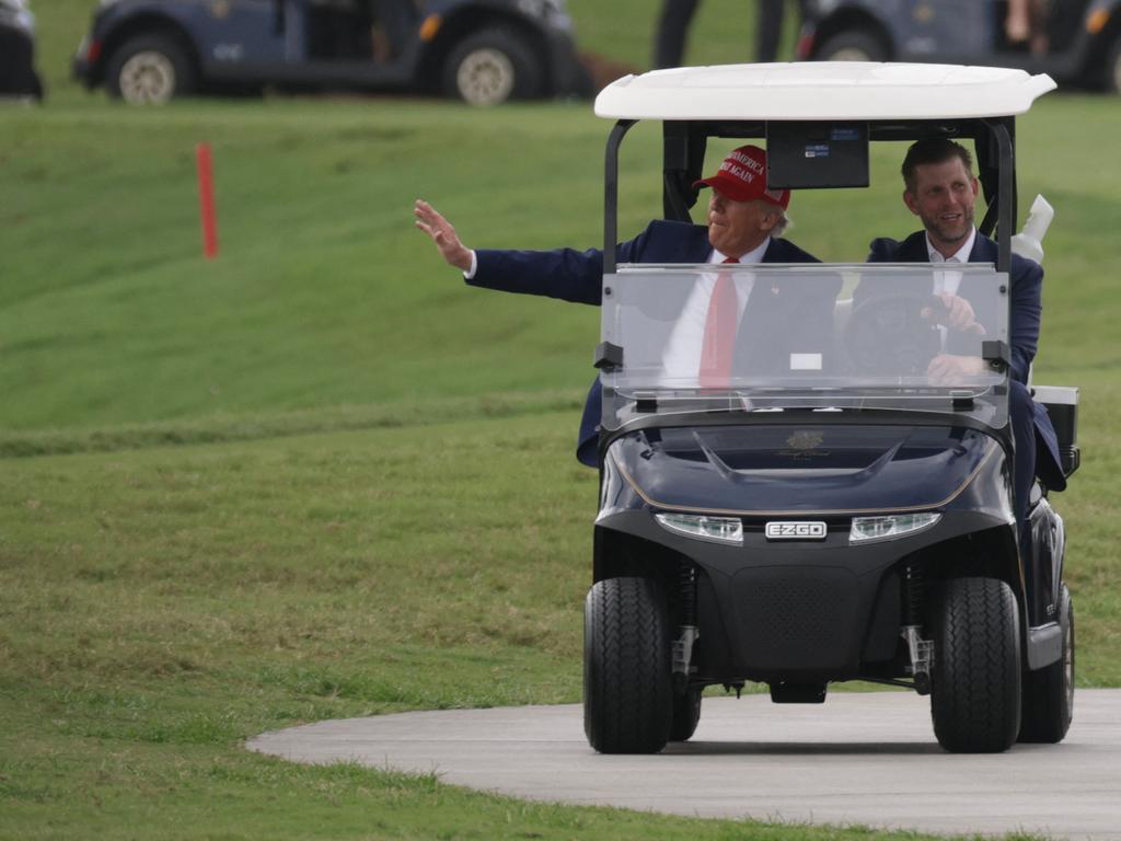 President Donald Trump and his son, Eric Trump, drive in a golf cart on the course where the shooting occurred. Picture: AFP