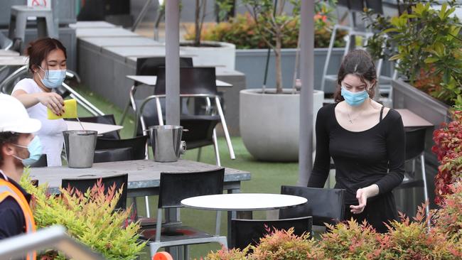 Staff clean tables in a cafe in Melbourne’s Federation Square in October. Picture: David Crosling