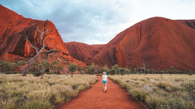 A tourist walking around the base of Uluru, near Alice Springs. Picture: Tourism NT/Jackson Groves