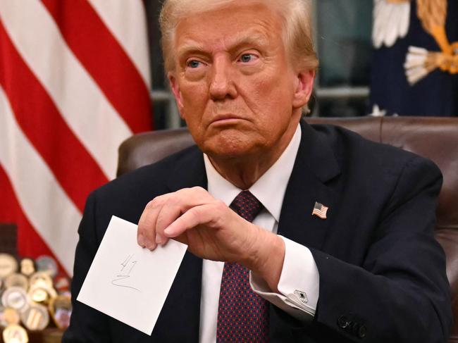 US President Donald Trump holds up outgoing President Joe Biden's letter as he signs executive orders in the Oval Office of the WHite House in Washington, DC, on January 20, 2025. (Photo by Jim WATSON / POOL / AFP) / ALTERNATE CROP