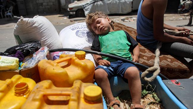 A boy sleeps on a sack of flour next to jerrycans in the back of an animal-drawn cart while evacuating from the Tuffah neighbourhood. Picture: AFP