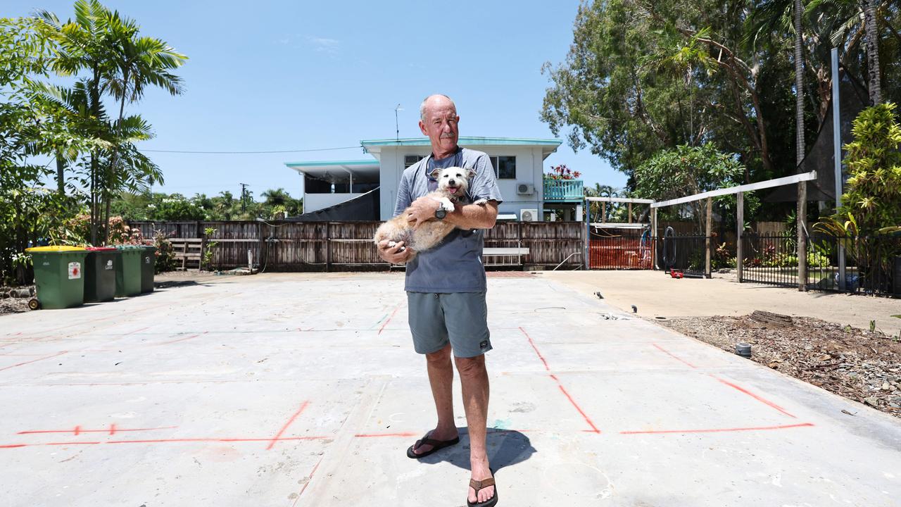 After having their Holloways Beach house badly damaged in last year's flood, Chris Tress and his wife have made the decision to demolish the existing structure and build a new, smaller kit home on the existing slab. The couple hope to have their new home completed by June. Chris Tress stands on the site of his old home with his dog Peg. Picture: Brendan Radke