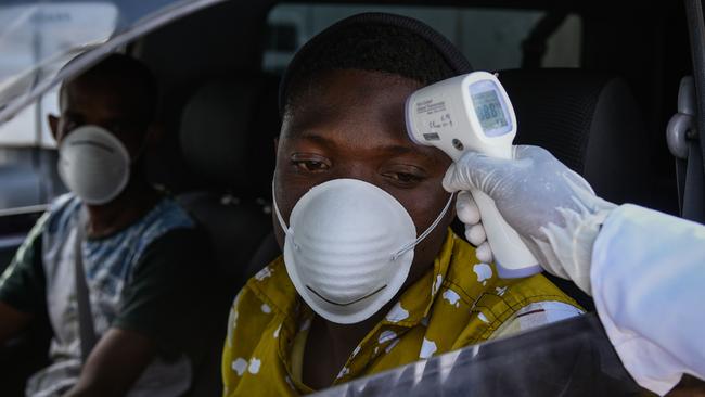 A staff member of the Kenyan Ministry of Health measures the temperatures of drivers and passengers during testing for Covid-19 on a highway in Nakuru. Picture: Suleiman Mbatiah/AFP