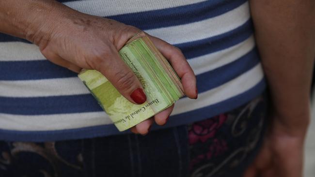 A woman holds a wad of bills to pay her bus fare in Caracas. Picture: Ariana Cubillos/AP