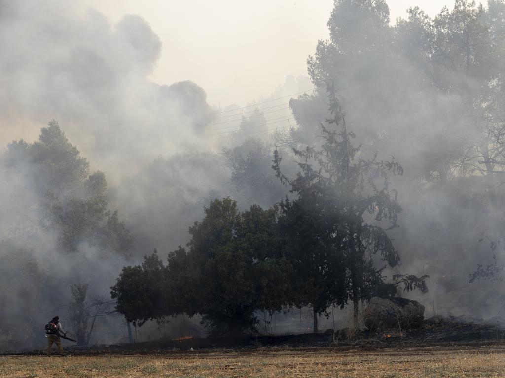 A firefighter uses a blower to control a fire that broke out after a rocket strike fired from Lebanon in Northern Israel. Picture: Getty Images