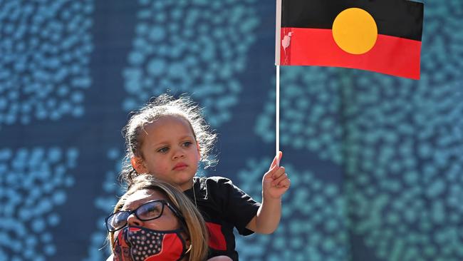 A young girl holds up an Australian Aboriginal flag during an ‘Invasion Day’ demonstration. Picture: Steven Saphore / AFP