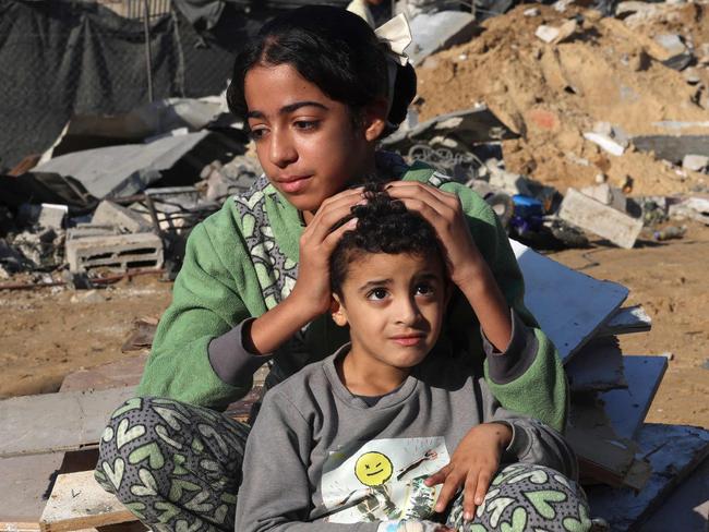 A Palestinian girl and her brother sit amidst the debris of a house following an Israeli strike in Rafah in the southern Gaza Strip on November 18, 2023, amid ongoing battles between Israel and the Palestinian group Hamas. (Photo by MOHAMMED ABED / AFP)