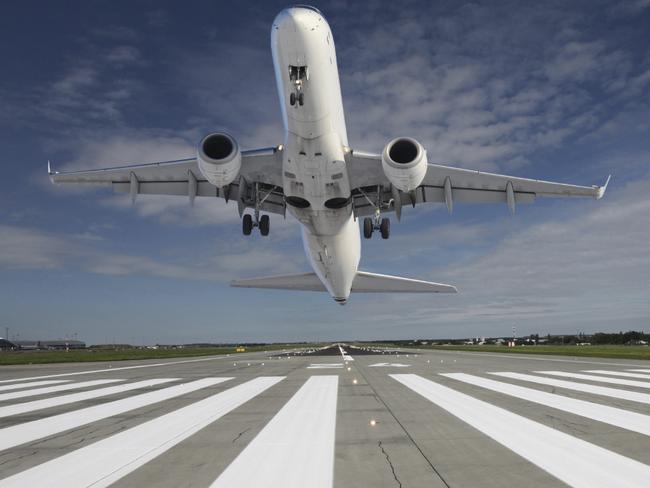 Plane taking off at the end of the runway with outstretched landing gear