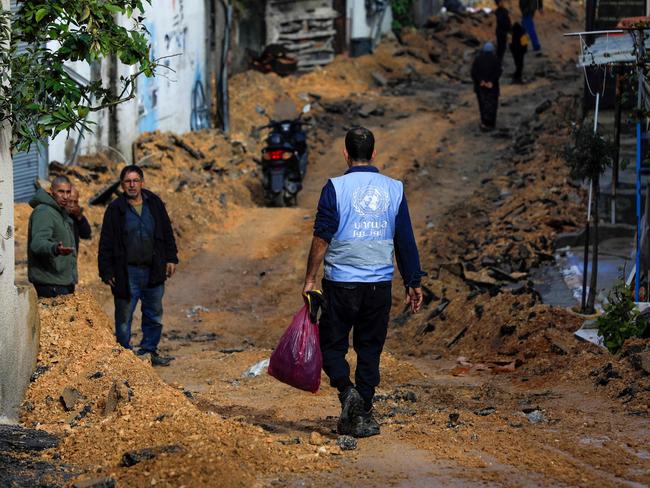 TOPSHOT - A man wearing a jacket of the UN agency for Palestinian refugees (UNWRA) walks on a street which has been bulldozed by the Israeli forces during a raid in Jenin in the occupied West Bank on January 29, 2024. (Photo by Zain JAAFAR / AFP)