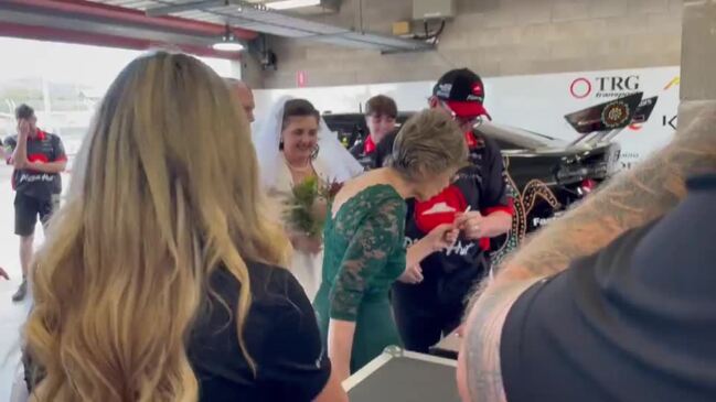 Newlyweds celebrate after marriage amidst Supercars garage