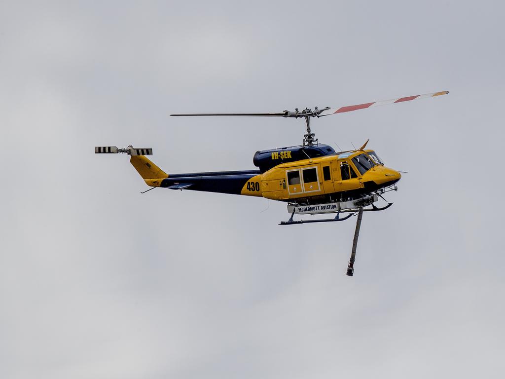 Smoke haze covers the Gold Coast Skyline from a grass fire at Carrara. A firefighting helicopter collects water from Judy Turners property in Carrara . Picture: Jerad Williams