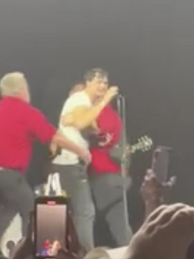 An unruly fan stormed the stage and was grabbed by security.