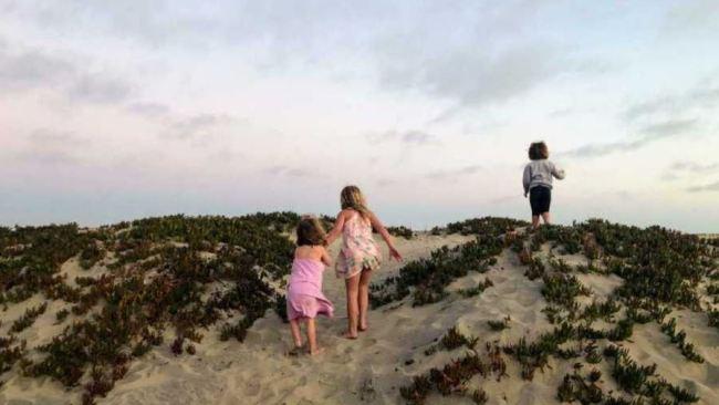 Emily helps her little sister climb up a sand dune. Picture: Supplied