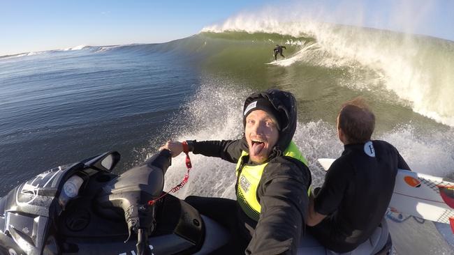 The Mad Hueys co-founder Joel Scott (driving jetski), Josh Dowthwaite on the back of the jetski and Mad Hueys co-founder Shaun Harrington surfing the wave.