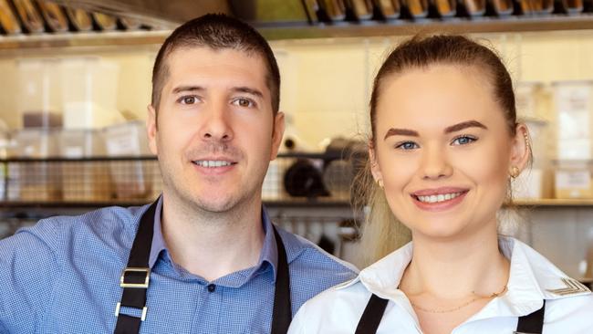 CAREERS FOR MAY 2: Portrait of small business owner smiling behind counter inside eatery, Successful young waiters working in apron holding food order for home delivery