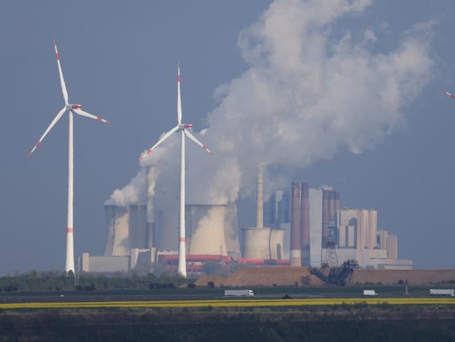 ERKELENZ, GERMANY - APRIL 21: Wind turbines spin as steam rises from the Neurath coal-fired power station at Neurath on April 21, 2022 near Erkelenz, Germany. The Neurath power station, which, according to data from 2020, is Europe's second biggest emitter of CO2, is supplied with lignite coal from the nearby Garzweiler II open-cast mine. While the German government is pursuing ambitious and accelerated goals for the country's transition away from fossil fuels and towards renewable energy sources, Germany remains dependent on coal for the near future. RWE, the energy company that owns the Garzweiler mine, recently won a court case that will allow it to raze what remains of the nearby village of Luetzerath, where a lone farmer, Eckhardt Heukamp, had been refusing to leave. Several settlements near Garzweiler as well as near other open-cast coal mines in Germany are slated for destruction to allow for mine expansion. Energy companies are offering resettlement to affected residents. (Photo by Sean Gallup/Getty Images)