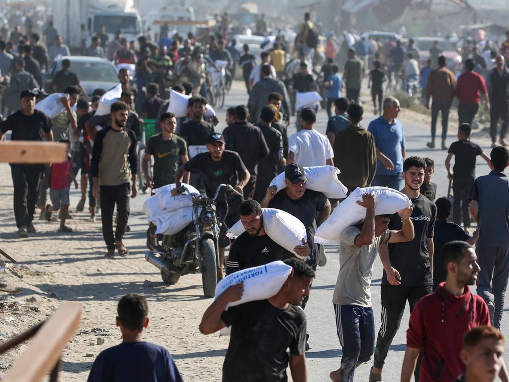 Palestinians carry bags of food aid after storming a World Food Programme warehouse in Deir el-Balah. Picture: AFP