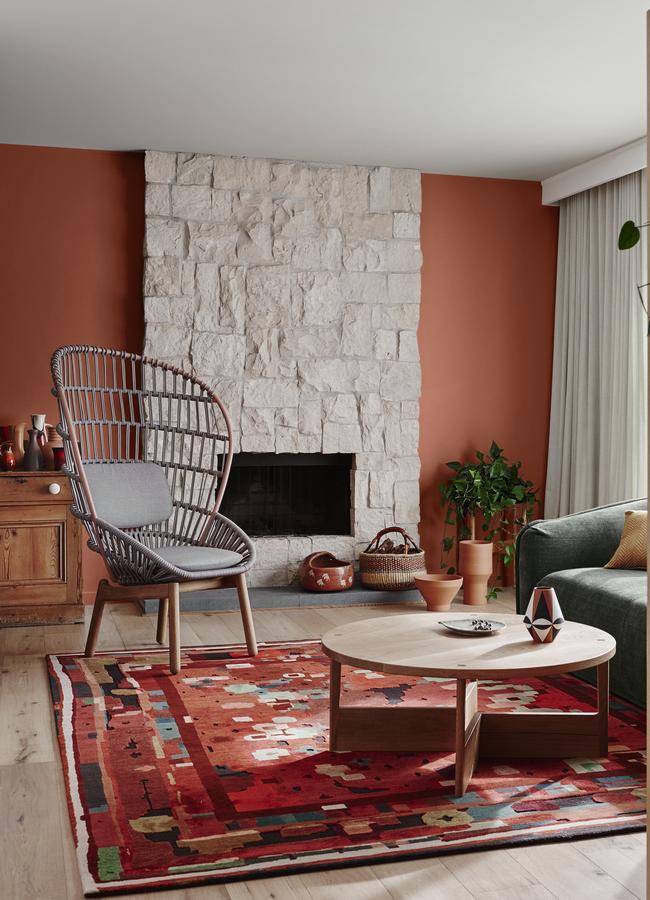 Very Terracotta from Dulux warms the soft greys of the stone fireplace. The whole scheme is pulled together by the rug with touches of soft green and deep ochre. Styling: Bree Leech. Picture: Lisa Cohen.