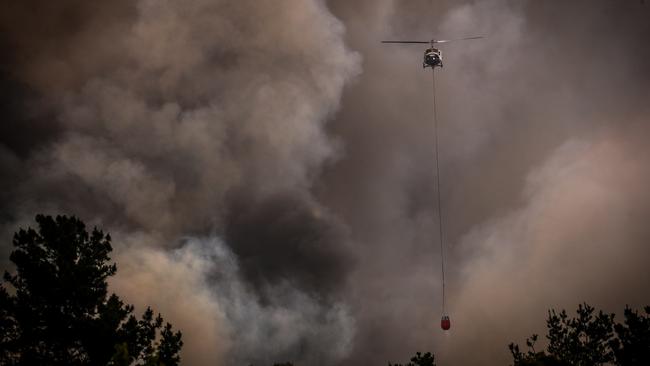 Helicopters dump water on bushfires as they approach homes on the outskirts of the town of Bargo on Saturday.