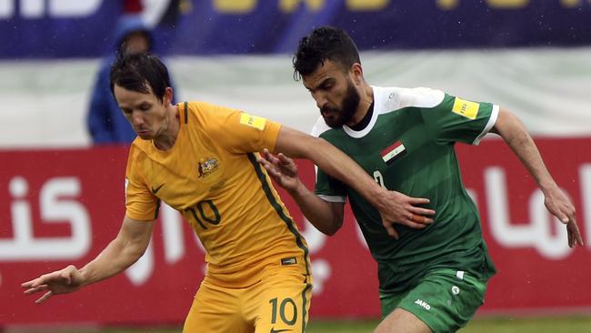 Australia's Robbie Kruse, left, plays the ball as he is followed by Iraq's Ali Bahjat Fadhil.
